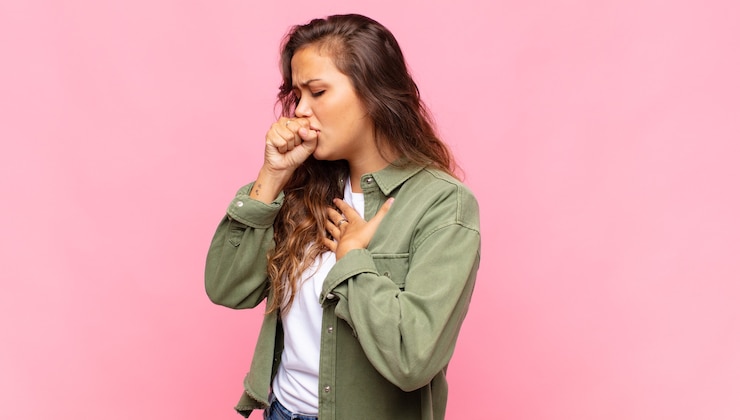 Foto mulher jovem e bonita tossindo em fundo rosa