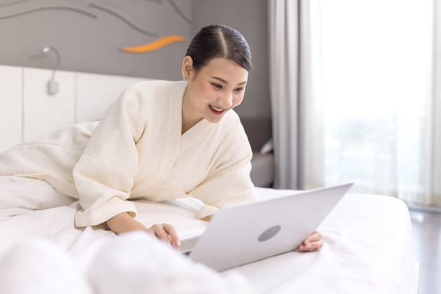 Mulher jovem e bonita trabalhando com laptop na cama