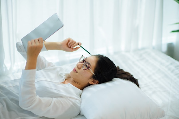 Foto mulher jovem e bonita trabalhando na cama, ela palestra e olhando o caderno. foco suave e suave