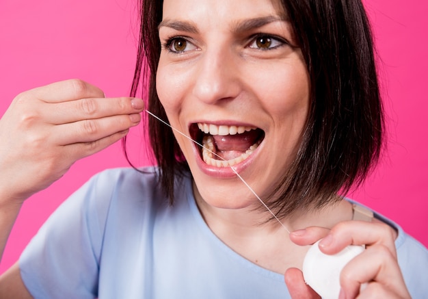 Mulher jovem e bonita usando fio dental em fundo rosa