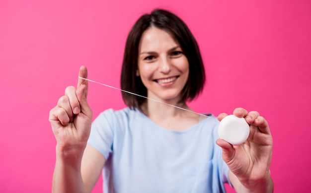 Mulher jovem e bonita usando fio dental em fundo rosa