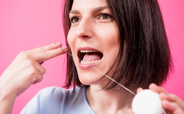 Mulher jovem e bonita usando fio dental em fundo rosa