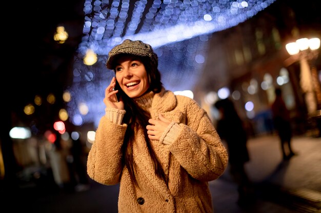 Mulher jovem e bonita usando o celular na rua na época do Natal