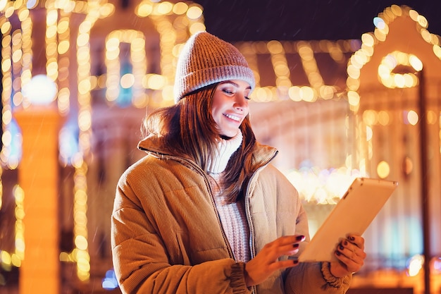 Mulher jovem e bonita usando seu tablet digital no inverno