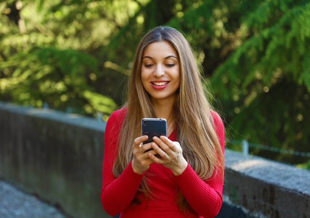 Mulher jovem e bonita usando telefone inteligente no parque