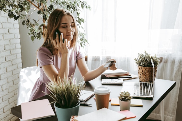 Mulher jovem e bonita usando telefone móvel em um escritório moderno