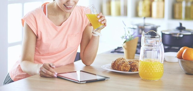 Mulher jovem e bonita usando um tablet digital na cozinha