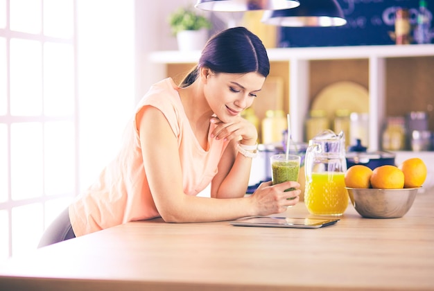 Mulher jovem e bonita usando um tablet digital na cozinha