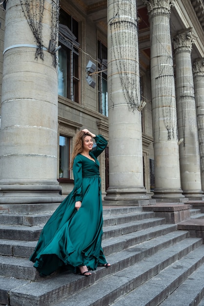 Mulher jovem e elegante em um lindo gramado verde em pé na escada de pedra, estilo de vida citadino