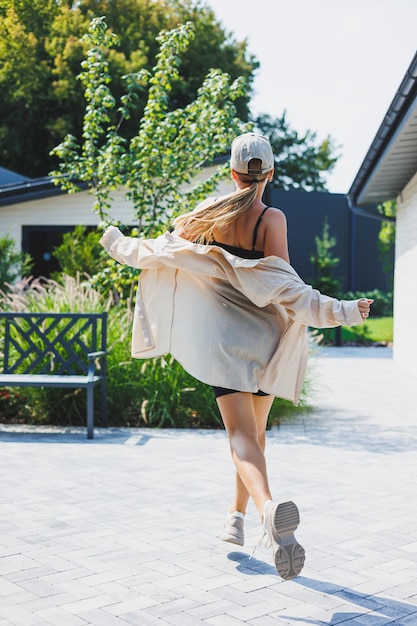 Mulher jovem e elegante em um top preto e shorts vestindo uma jaqueta grande uma garota elegante anda pela rua óculos de sol elegantes de moda de verão