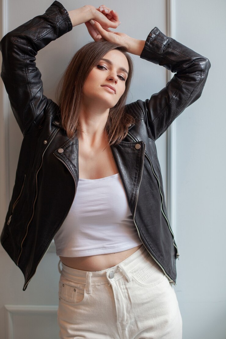 Foto mulher jovem e encantadora posando de jaqueta de couro preta e calça jeans branca sobre um fundo branco. beleza, moda.