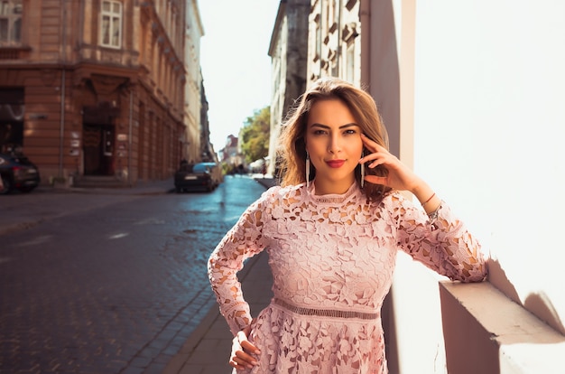 Mulher jovem e encantadora posando na rua em um dia ensolarado. Mulher usando vestido de renda da moda