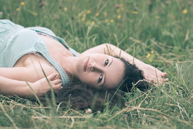 Mulher jovem e encantadora relaxando no pasto em um dia de verão. foto com espaço de cópia