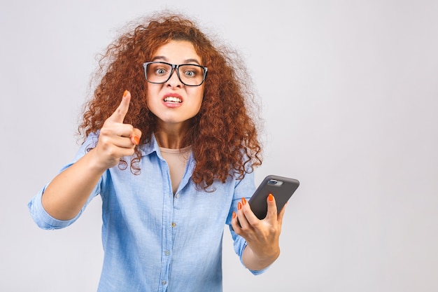 Mulher jovem e encaracolada irritada falando ao telefone, isolado em um fundo branco