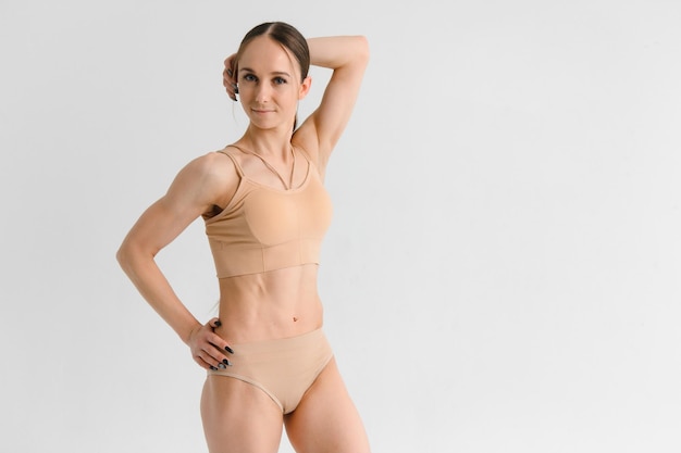 Mulher jovem e esportiva em roupas íntimas posando no fundo branco do estúdio com espaço para cópia dieta fitness cuidados com o corpo conceito de beleza feminina