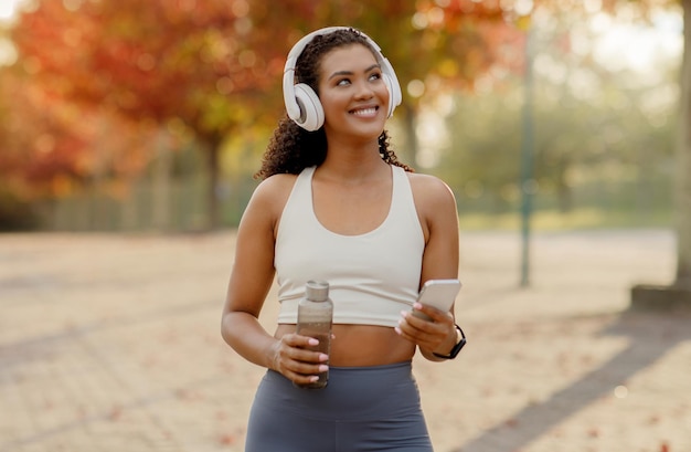 Foto mulher jovem e esportiva ouvindo música no telefone com fones de ouvido ao ar livre