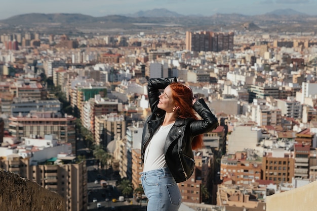 Mulher jovem e feliz bonita aprecia a vista da cidade