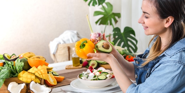 Mulher jovem e feliz comendo salada na mesa