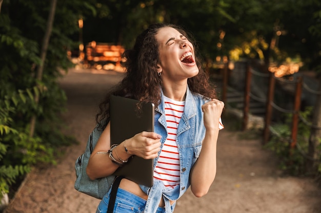 Mulher jovem e feliz segurando um laptop