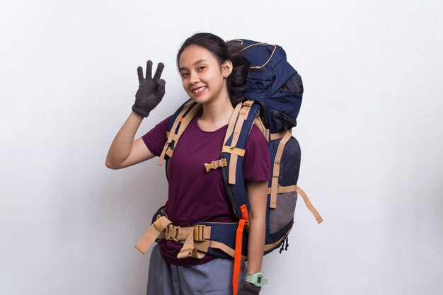 Mulher jovem e linda alpinista asiática com mochila mostrando um gesto de ok com o polegar para cima no fundo branco