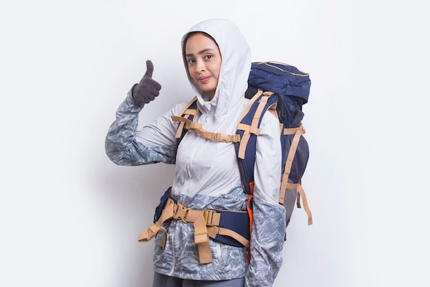 Mulher jovem e linda alpinista asiática com mochila mostrando um gesto de ok com o polegar para cima no fundo branco