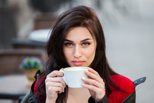 Mulher jovem e linda com uma xícara de café na rua da cidade