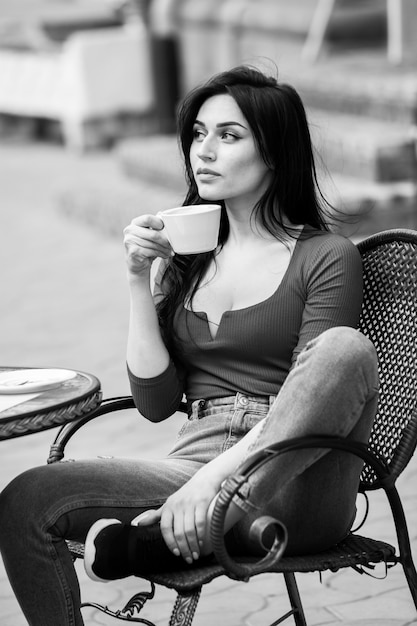 Mulher jovem e linda com uma xícara de café na rua da cidade