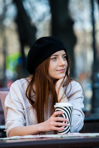 Mulher jovem e linda com uma xícara de café na rua da cidade