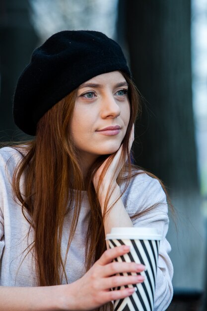 Mulher jovem e linda com uma xícara de café na rua da cidade