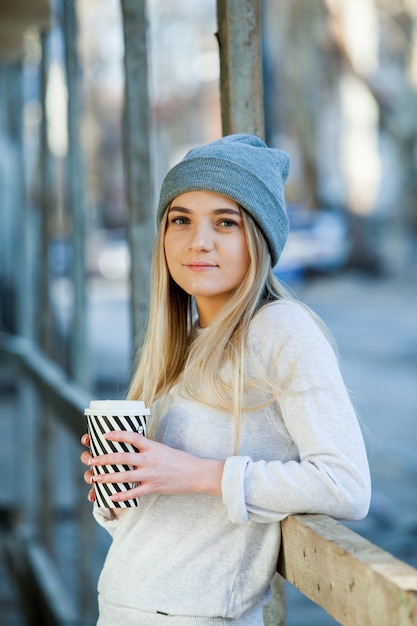 Mulher jovem e linda com uma xícara de café na rua da cidade