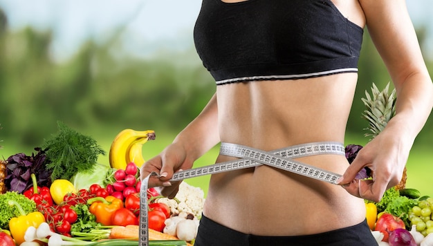 Foto mulher jovem e magra medindo a cintura fina com uma fita métrica, close-up