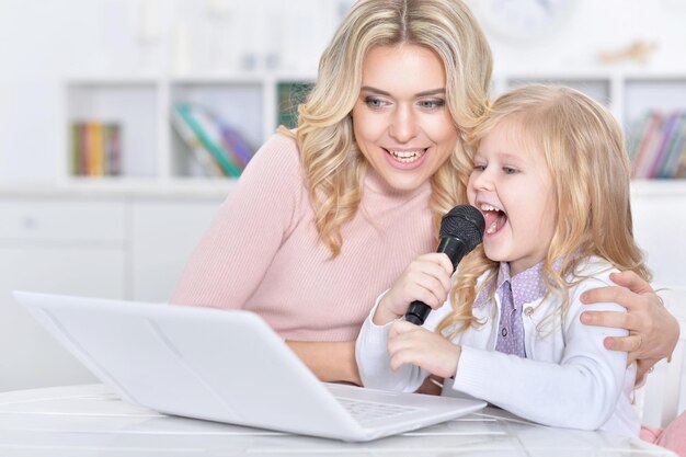 Mulher jovem e menina cantando karaokê