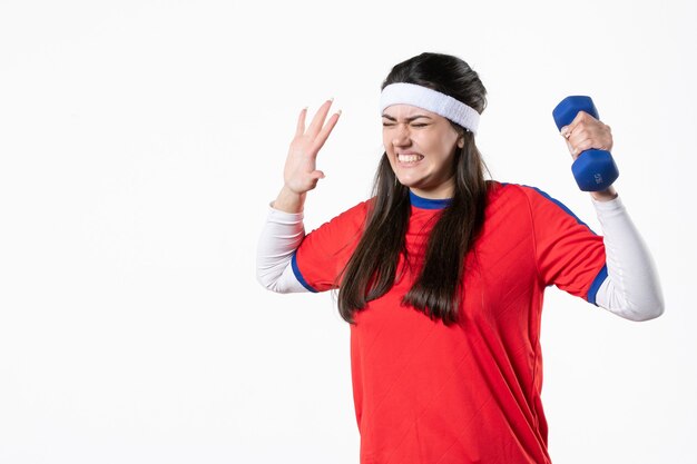 Foto mulher jovem e nervosa de frente com roupas esportivas e halteres azuis