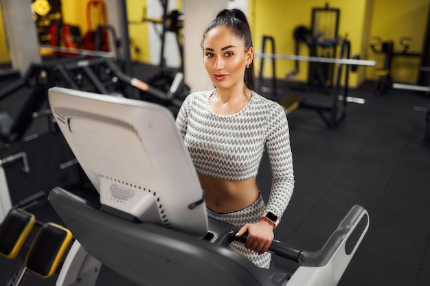 Mulher jovem e saudável com exercícios aeróbicos em uma esteira na academia