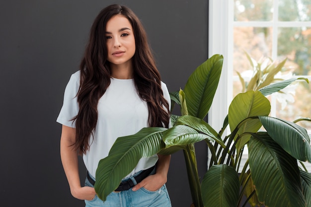 Foto mulher jovem e séria posando perto de uma janela