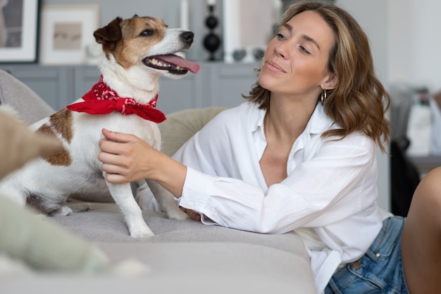 Foto mulher jovem e seu cachorro no sofá em casa. adorável animal de estimação. animal doméstico