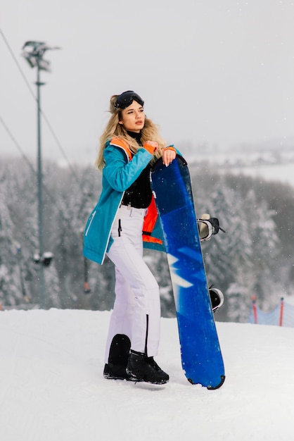 Mulher jovem e sorridente desportiva no inverno com snowboard, óculos