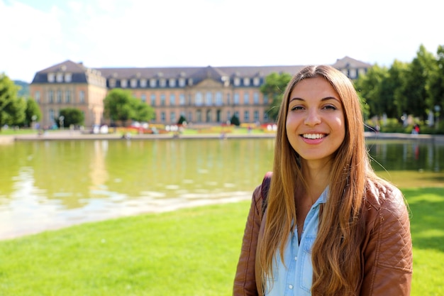 Mulher jovem e sorridente em frente ao Neues Schloss de Stuttgart, Alemanha