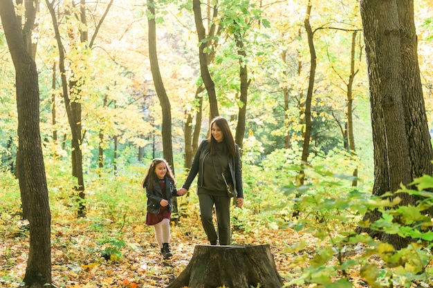 Mulher jovem e sua filha caminhando pelo parque mãe solteira e conceito de maternidade