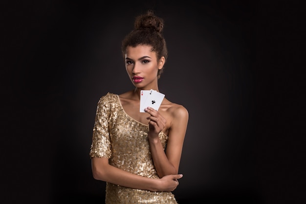 Mulher jovem e vencedora com um elegante vestido dourado segurando dois ases uma combinação de cartas de pôquer de ases