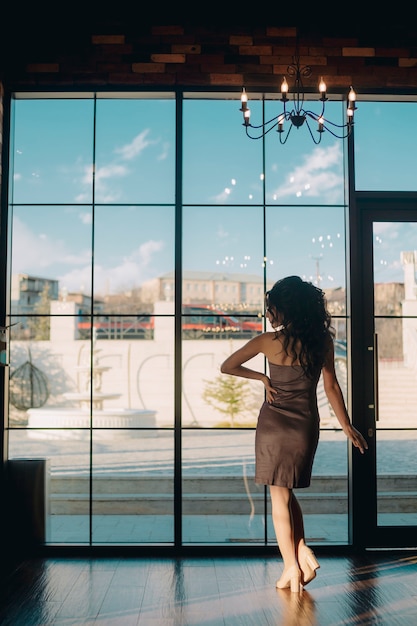Foto mulher jovem elegante em frente a uma porta de vidro deslizante em um restaurante de luxo