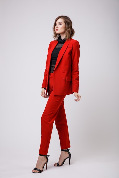 Mulher jovem elegante em uma calça de paletó muito vermelho calças blusa preta sobre fundo branco