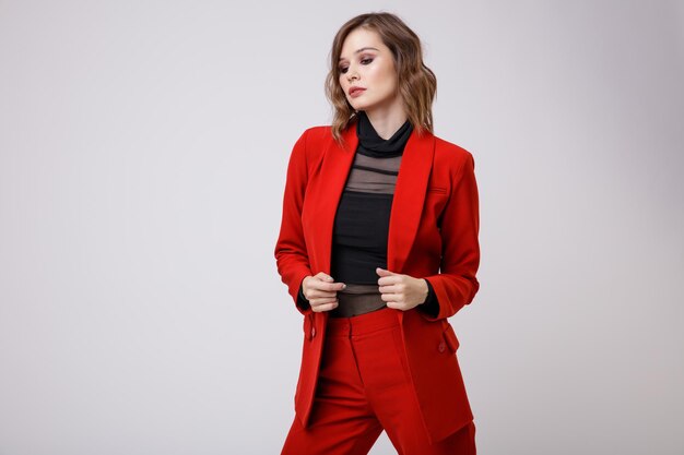 Mulher jovem elegante em uma calça de paletó muito vermelho calças blusa preta sobre fundo branco