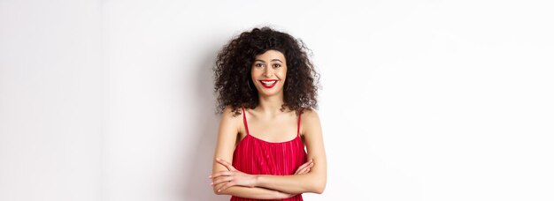 Mulher jovem elegante em vestido vermelho com maquiagem vestida para evento festivo sorrindo feliz na câmera sta