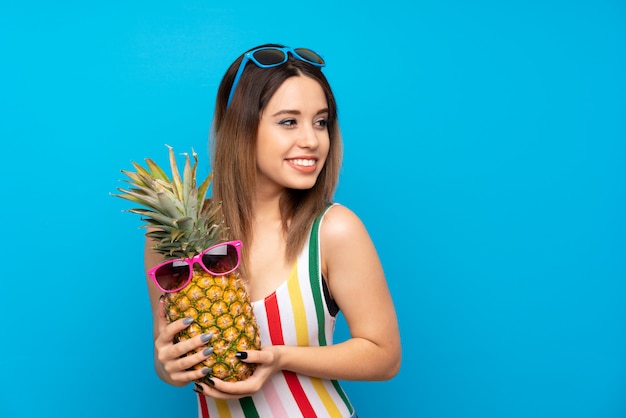 Mulher jovem, em, férias verão, sobre, azul, segurando, um, abacaxi, com, óculos de sol