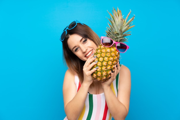 Mulher jovem, em, férias verão, sobre, azul, segurando, um, abacaxi, com, óculos de sol