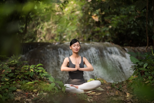 Mulher jovem, em, ioga posa, sentando, perto, cachoeira