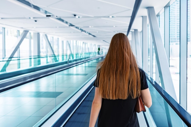 Mulher jovem em pé na escada rolante do metrô