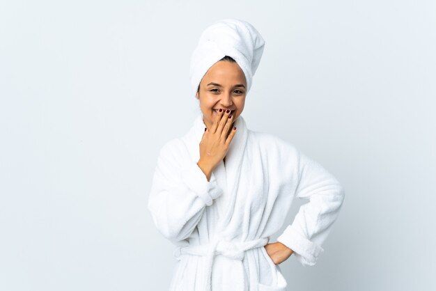 Mulher jovem em roupão de banho sobre branco isolado feliz e sorridente cobrindo a boca com a mão