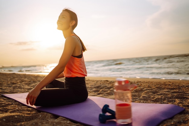 Mulher jovem em roupas esportivas fazendo exercícios de fitness de ioga na praia Esporte Vida ativa